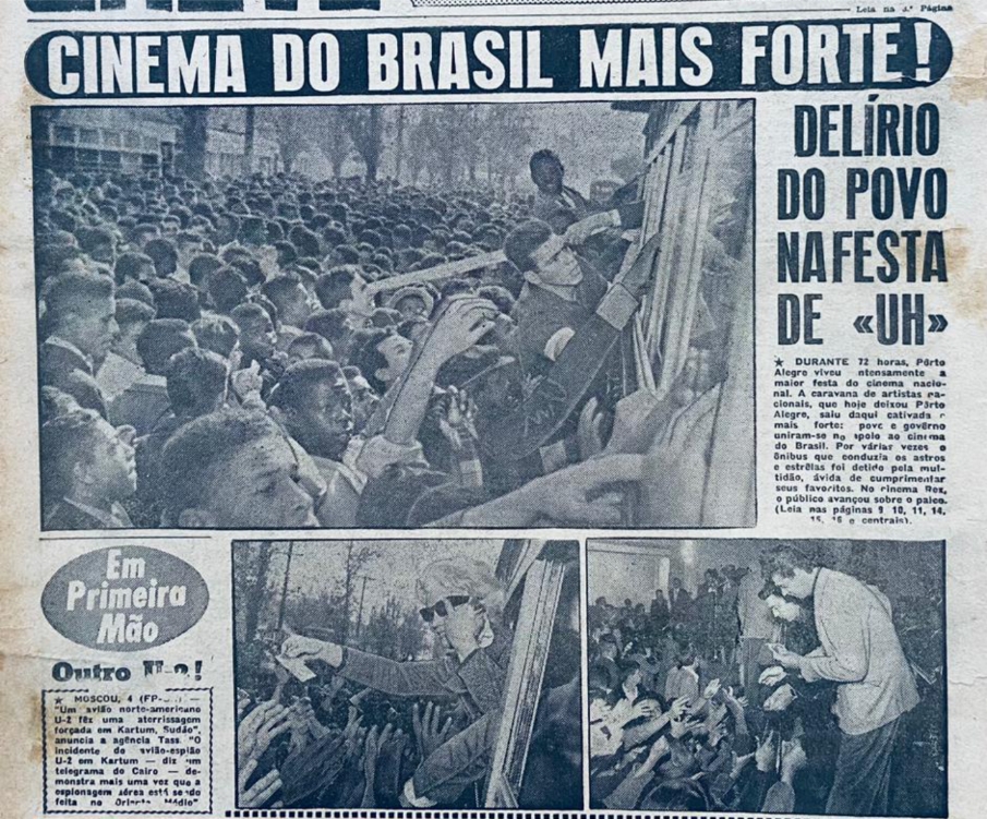 Imagem em preto e branco de capa do Jornal Última Hora de 4 de Julho de 1960, Na parte superior, a inscrição “Cinema Do Brasil Mais Forte!”. Logo abaixo, à esquerda, fotografia mostra multidão aglomerada em frente a ônibus, com destaque para dois homens pendurados no mesmo. Ao lado da foto, manchete “Delírio do povo na festa de ‘UH’”, seguido de texto. Na parte inferior esquerda da imagem, balão ovalado com a inscrição “Em primeira mão”, seguido de texto. Ao lado direito destes, duas fotografias, a primeira mostra multidão assediando atriz em janela de ônibus; na segunda, multidão assedia ator que está em primeiro plano, à direita da imagem, vestindo casaco de tonalidade clara. [Fim da descrição]
