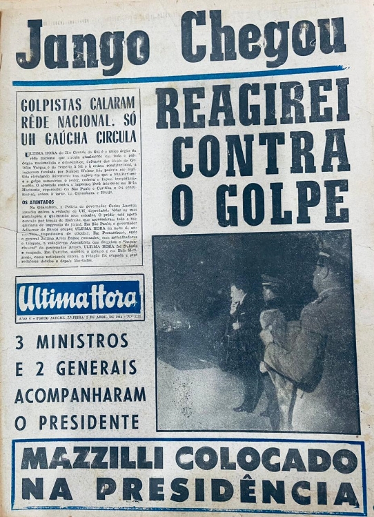 Fotografia da capa do Jornal Última Hora, do dia 1 de abril de 1964. Na parte superior, lê-se a manchete “Jango Chegou”. Abaixo desta, faixa em azul, e logo abaixo, à esquerda, caixa de texto com a inscrição “golpistas calaram rede nacional. Só UH gaúcha circula”, com texto logo abaixo. À direita desta caixa, Manchete com os dizeres “Reagirei contra o golpe”. Abaixo desta, à direita da capa, uma fotografia em preto e branco mostra dois militares de perfil em primeiro plano, com um homem de terno em tons escuros ao lado destes. Ao lado desta imagem, à esquerda da capa, logotipo em azul do Jornal Última Hora. Abaixo do mesmo, a inscrição “3 ministros e 2 generais acompanham o presidente”. Por fim, na parte inferior da capa, em uma caixa de texto com molduras em azul, a inscrição “Mazzilli colocado na presidência”. [Fim da descrição]