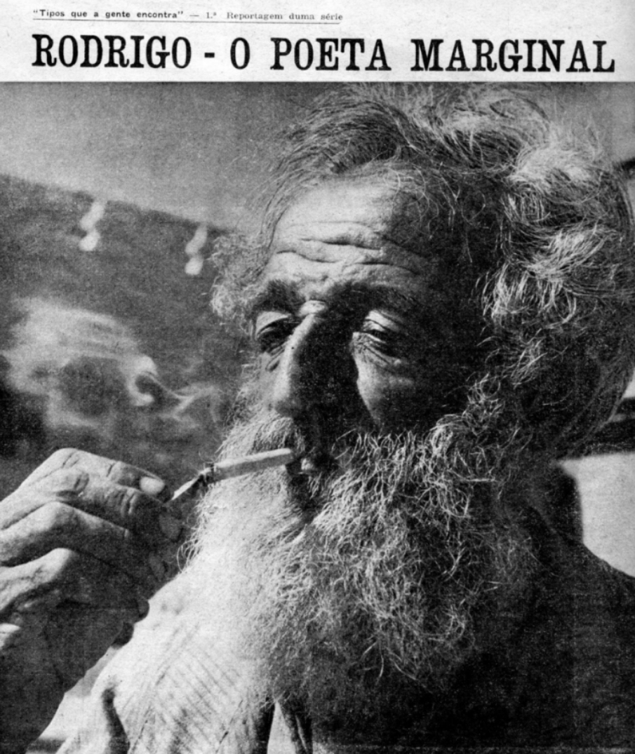 Fotografia em preto e branco no centro da cidade de Porto Alegre em  1945, um homem  aparentando meia idade, magro, rosto com rugas bem marcadas, com barba branca comprida e cabelo branco curto. Com um cigarro na boca e em uma das mãos enrugada acende o cigarro. [Fim da descrição]    