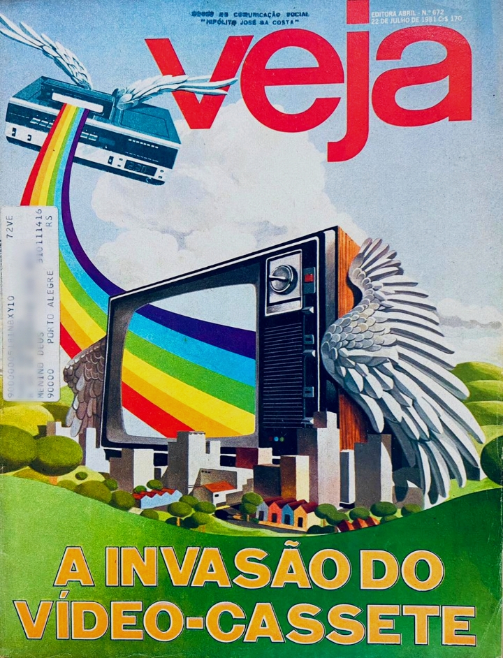 Imagem  vertical da capa da revista Veja de 1981. A capa é composta por imagens e textos.  Na parte superior está o nome  Veja, centralizado ,  a imagem de uma paisagem onde há edifícios e casas. Destaca-se uma televisão gigante com asas. De dentro dela sai um arco íris que tem na  extremidade um videocassete com asas sobre  céu azul e nuvens. Na parte inferior o texto “A invasão do vídeo-cassete”. [ Fim da descrição]